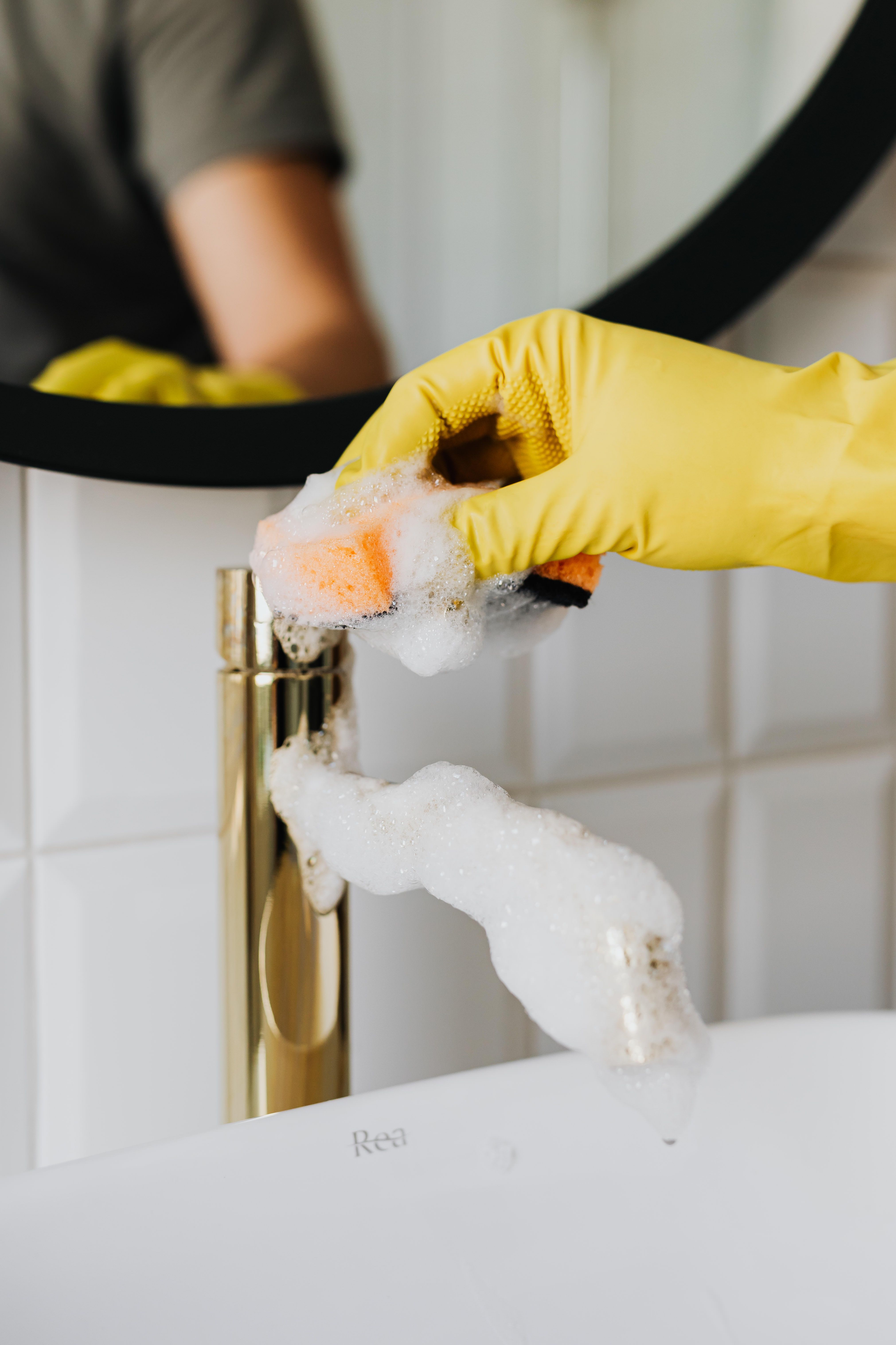 Gloved hands deep-cleaning a bathroom fixture until it shines